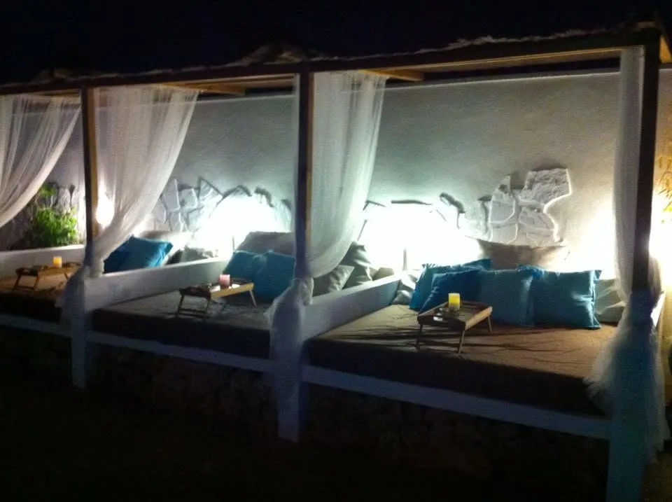 Camas balinesas con cortinas blancas iluminadas con luz cálida de noche