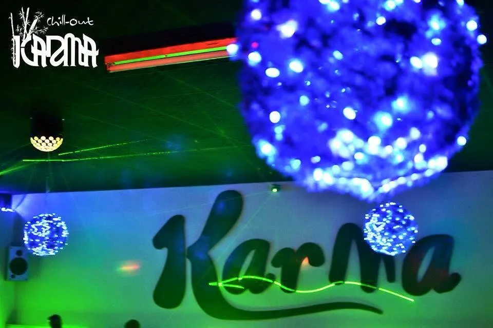 Rótulo de neón Karma en la discoteca, con bolas de luz azul y láser verde